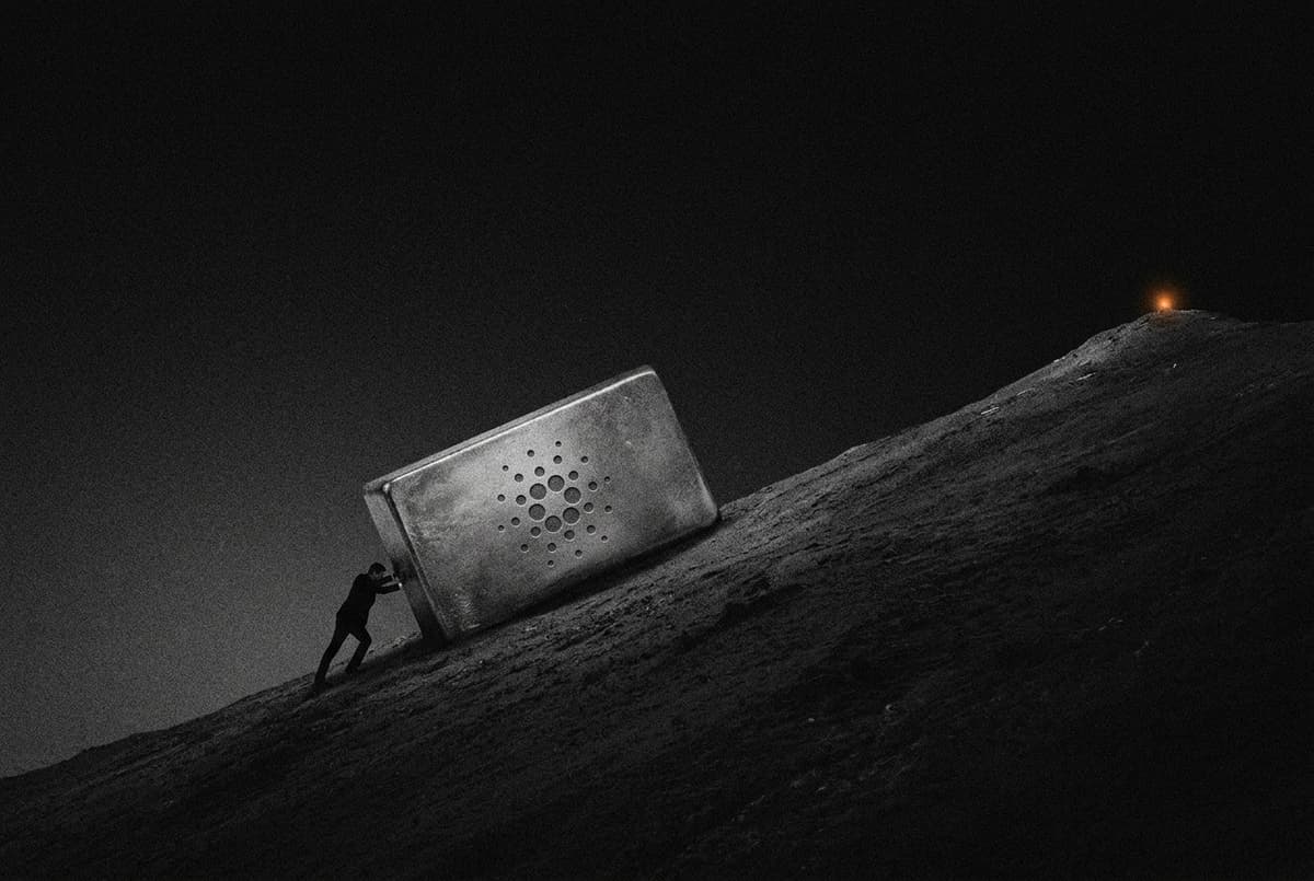 A small silhouette strains to push a large copper ingot bearing the Cardano mark up a steep slope toward a distant summit.