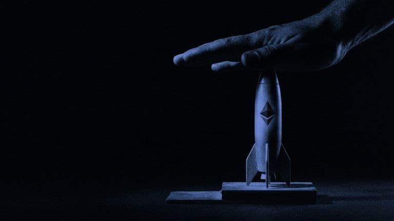 A giant hand presses down on the nose of a small rocket marked with the Ethereum logo, holding it on its launch pad in the dark.